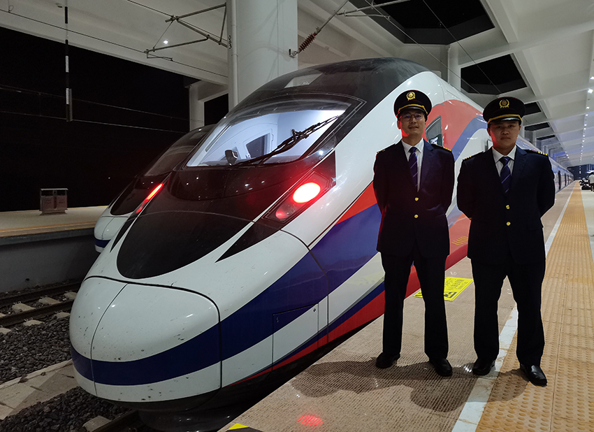 劉銀能（右一）與中國師父鄔俊鴻在動車組前合影。受訪者供圖