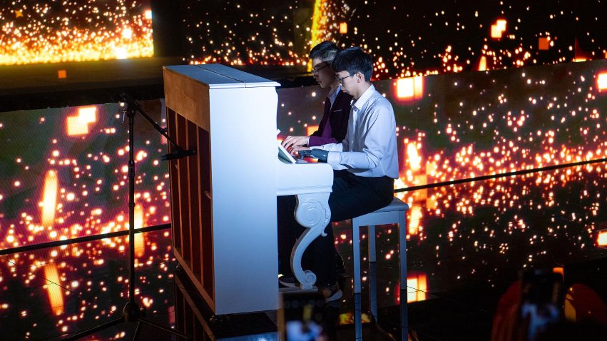 智能仿生手使用者古月與少年鋼琴家舒海峰合奏。主辦方供圖